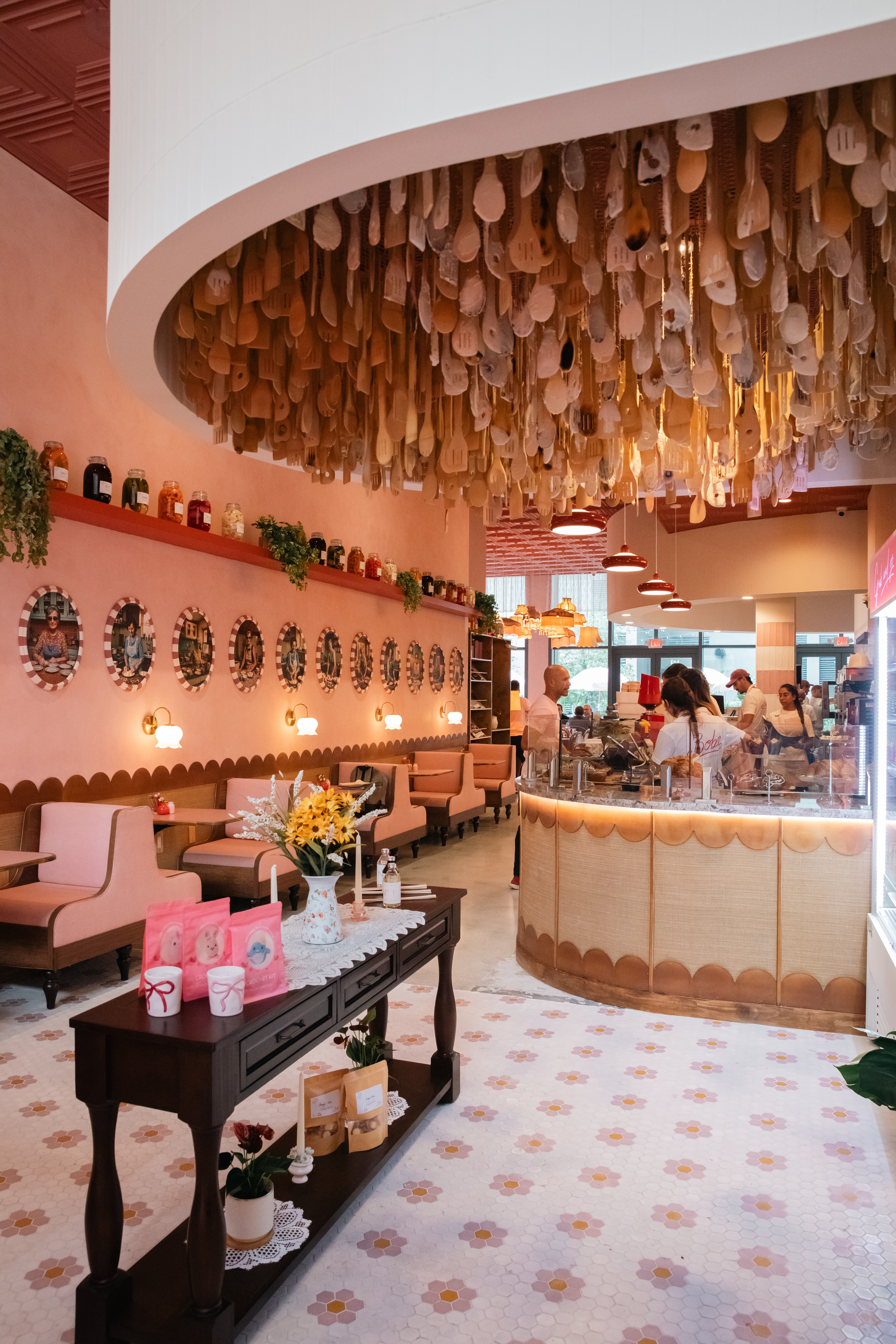 Interior of a decorated room with pink walls, wreaths, and hanging ornaments, featuring a seating area and a display counter.