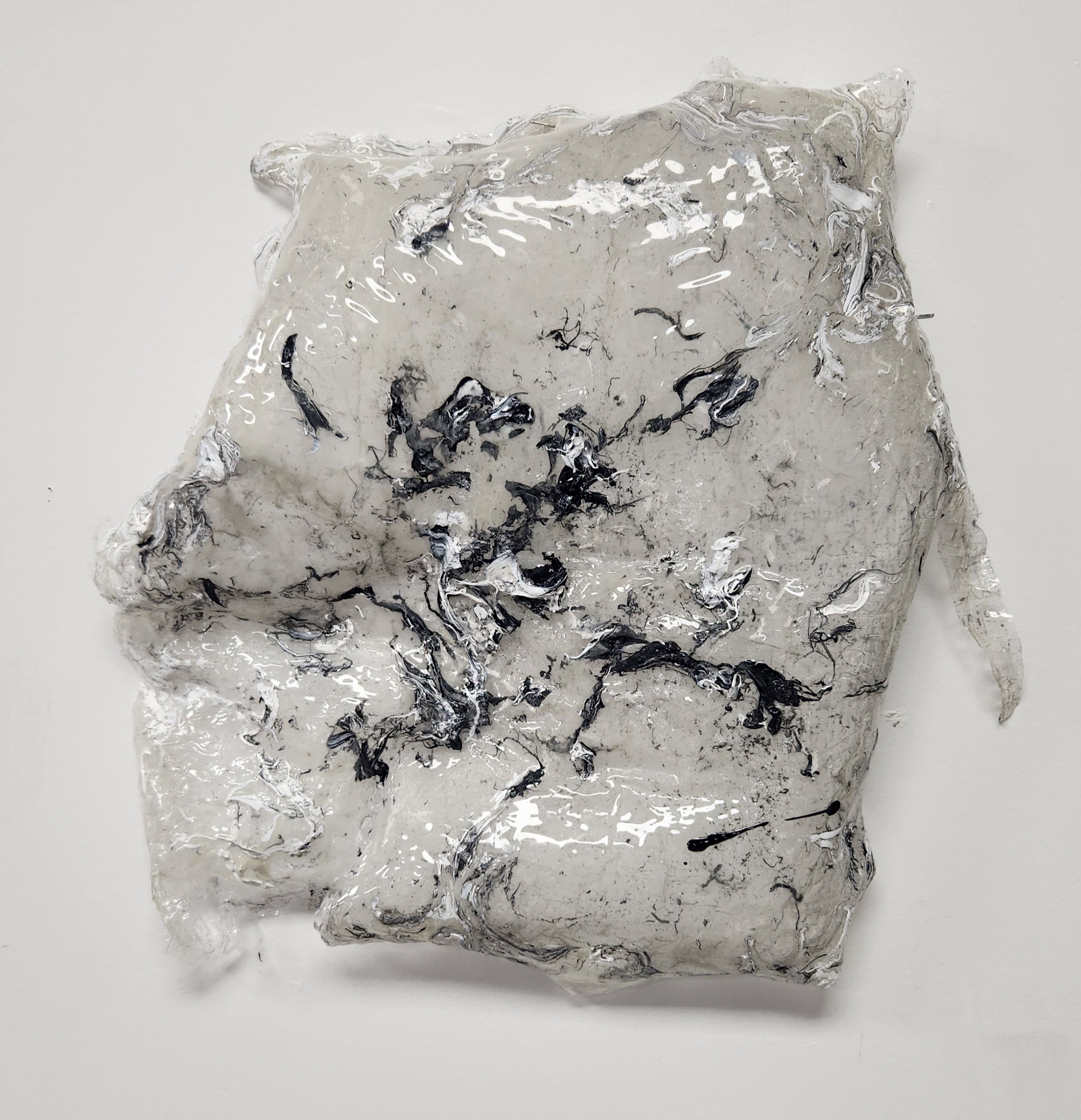 Crumpled, shiny, metallic-looking material with black streaks on a white background.